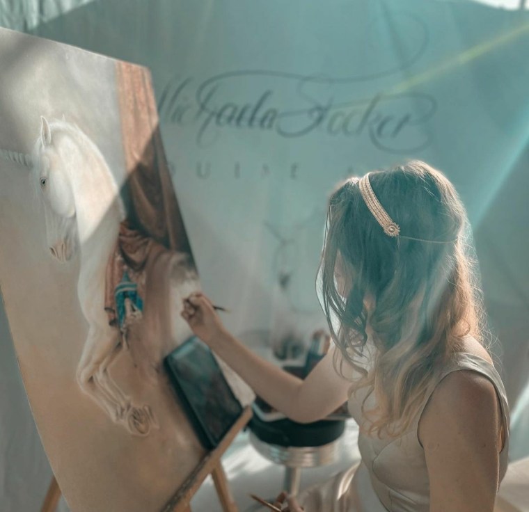 Pferdemalerin und Künstlerin Michaela Stocker malt ein Einhorn auf Papier in Pastelltechnik, umgeben von beeindruckendem Licht und einem eleganten Hintergrund in der Joseph-von-Fraunhofer-Halle in Straubing anlässlich eines Beethoven Konzerts im Rahmen von Klassik an der Donau.