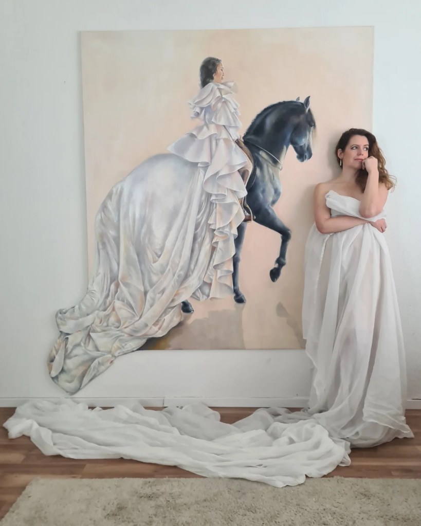 Das Gemälde zeigt die rennomierte Pferdetrainerin und Showreiterin Kenzie Dyslie, die elegant im weißen, voluminösen Kleid auf ihrem glänzenden, Rapphengst Fideo sitzt. Das Werk ist anmutig und fantasievoll, mit fließenden Stoffen, die aus der Leinwand herauszuwirken scheinen, und einer sanften, irisierenden Farbpalette.