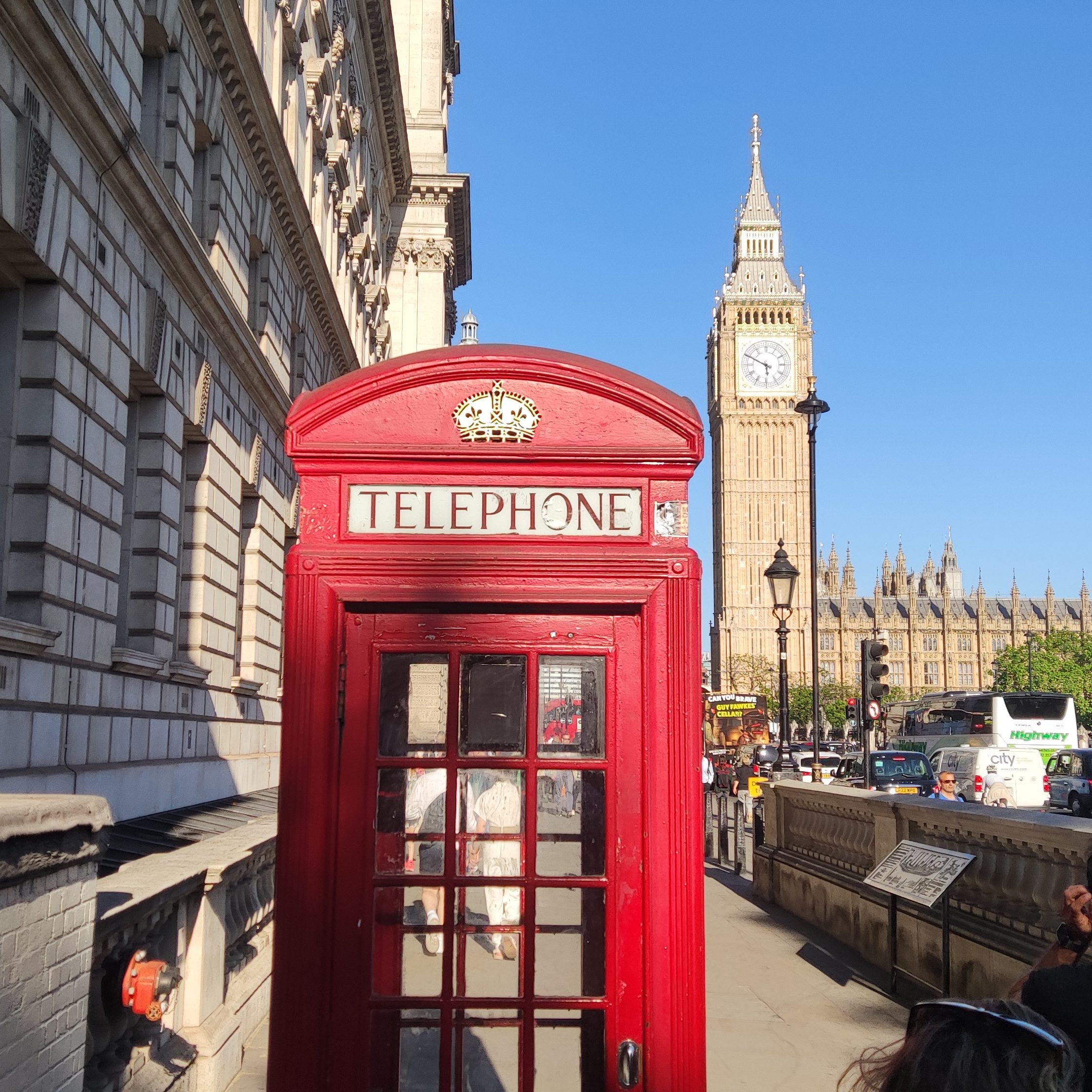 Ein roter Telefonzelle im Vordergrund mit dem Big Ben und der Houses of Parliament im Hintergrund an einem sonnigen Tag in London.