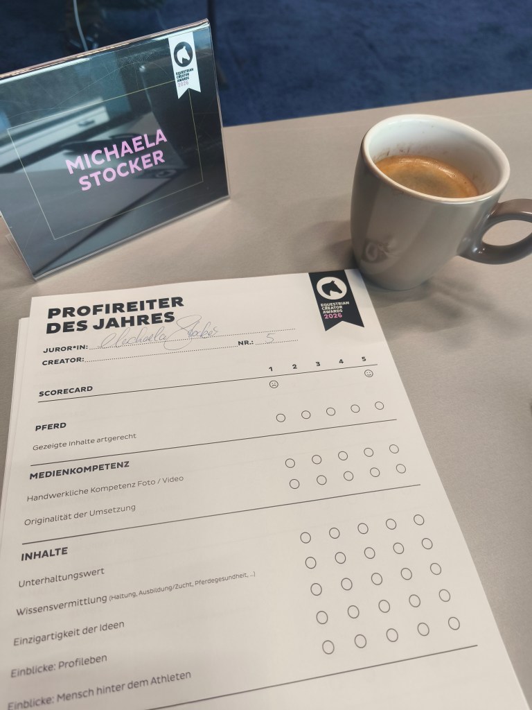 A table setting featuring a nameplate for Michaela Stocker, a juror at the Equestrian Awards 2026, next to a scorecard and a coffee cup.